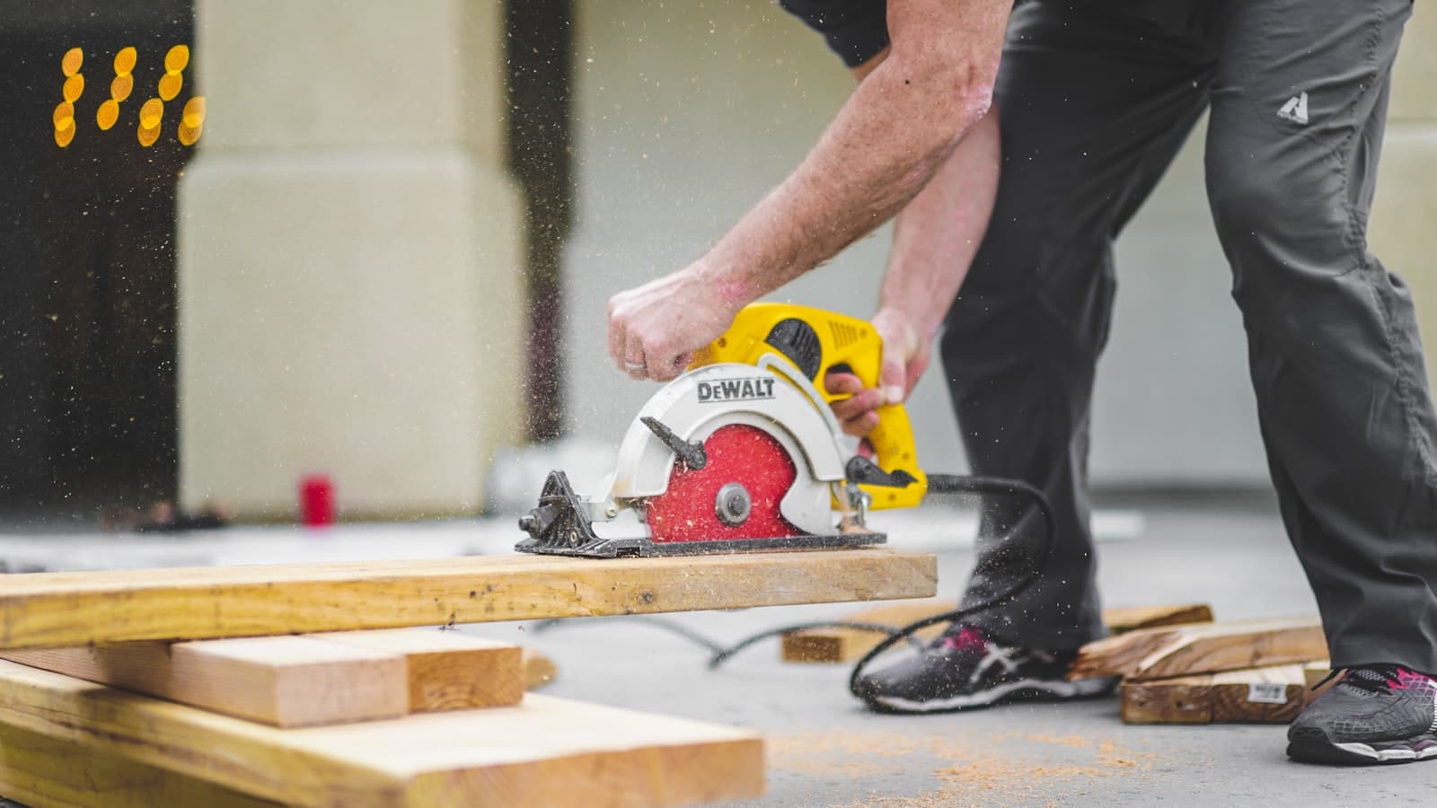 Un artisan découpe une planche à la scie circulaire sur un chantier.